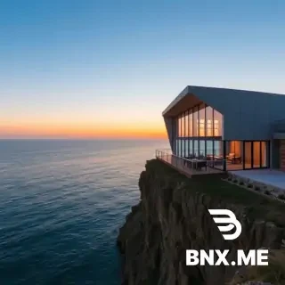A modern architectural building with large glass windows, situated on a cliff overlooking a serene ocean at sunset.