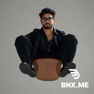 Create a hyper-realistic image of a 26-year-old young man sitting on a brown sandal, with black hair, hazel eyes, a charming beard, glasses, a muscular body, wearing a black shirt with the first button undone, black cloth pants, a black jacket, a gold chain hanging from his neck, and black shoes. The background is a pale black color, there is diffuse lighting from different directions, 4K quality, he is sitting in the sandal upside down, the camera angle is from behind, the back of the sandal is visible and the man is sitting upside down, an attractive and cool photo.